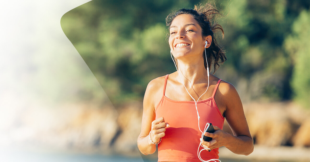 Woman running with headphones in and smiling to music.