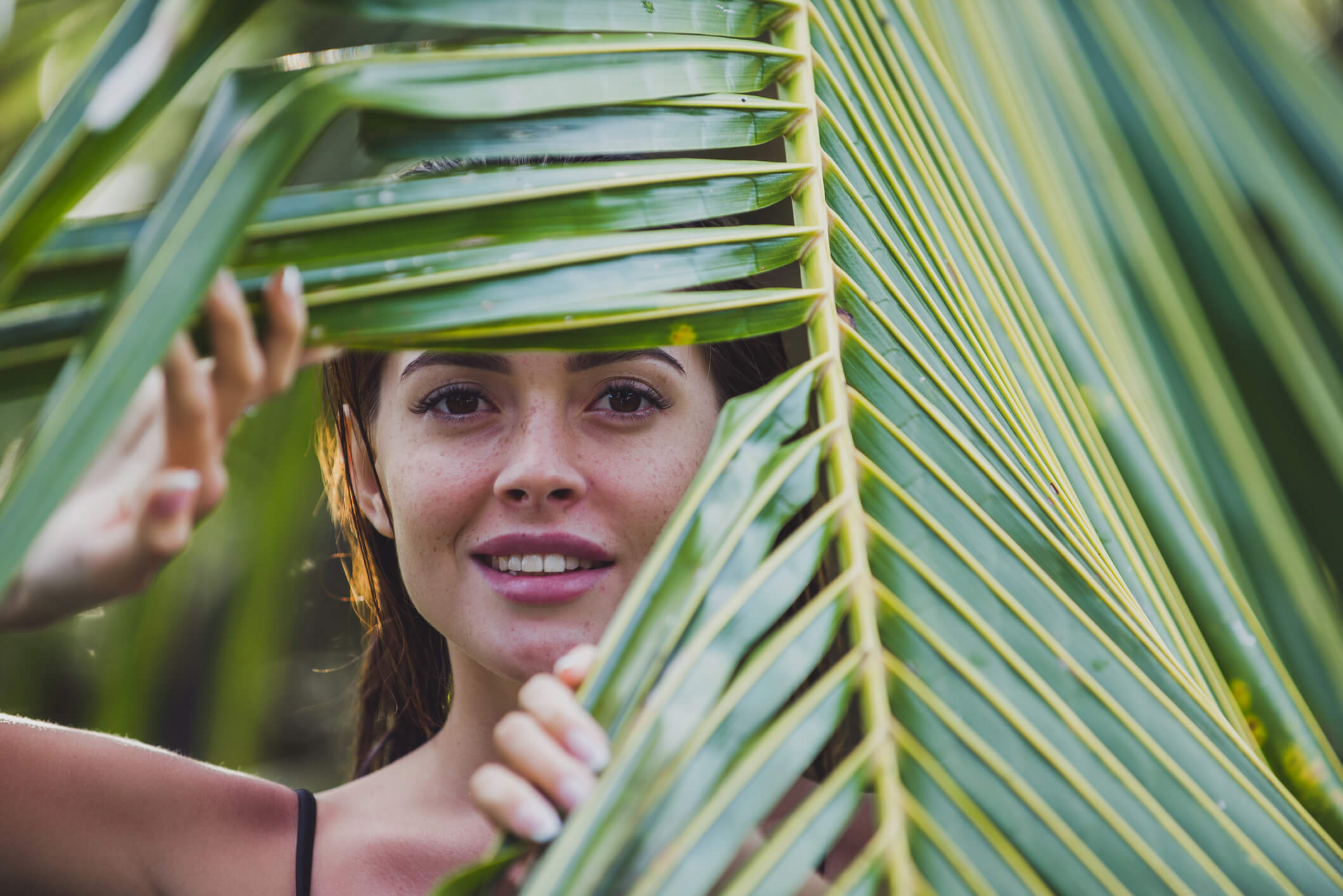 Woman peaking through a plant leaf
